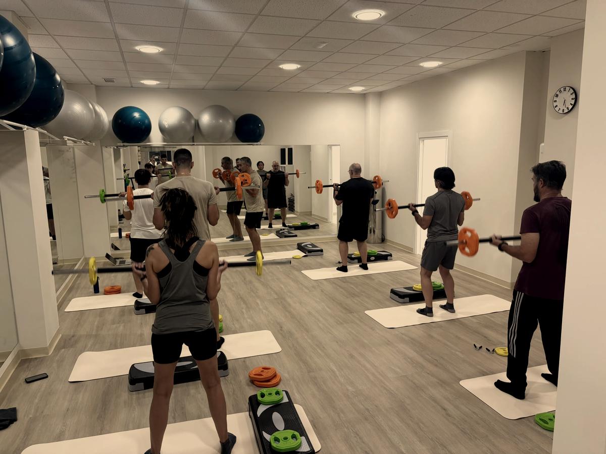 Alumnos trabajando de pie con barra frente al espejo de la sala